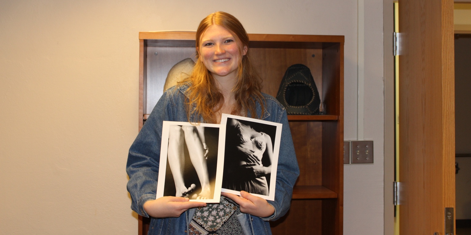2023 Fine Arts Award winner Lydia Norton holding prints of two black and white photos